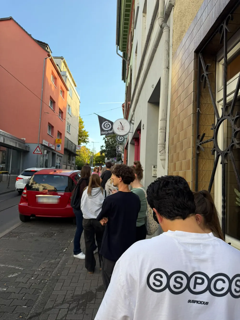 Wartende Menschen vor GAUST in der Gaustraße, Mainz, mit GAUST-Fahne an der Hauswand