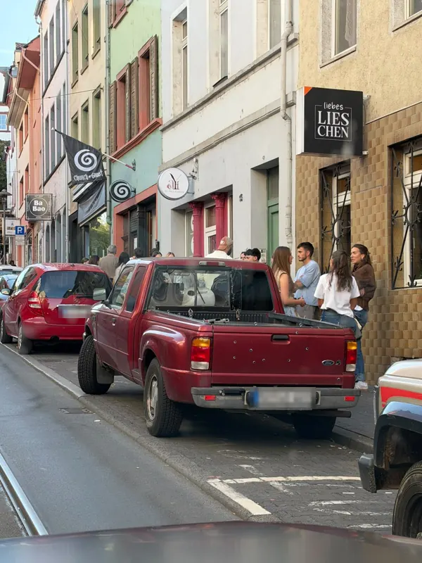 Gaustraße in Mainz mit GAUST-Fahne und Menschen, die vor dem Laden warten